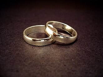 Un par de anillos de boda metálicos sobre una superficie lisa.