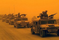 Convoy de vehículos militares durante una tormenta de arena