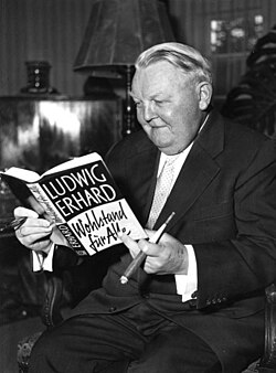 Ludwig Erhard sosteniendo su obra literaria económica en 1957.