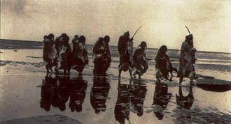 Grupo selk'nam caminando en una playa en 1930