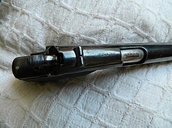 Número de serie visible en el armazón de un arma de fuego, específicamente una pistola semiautomática.