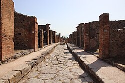 Calle pavimentada de Pompeya con aceras y bloques de paso.