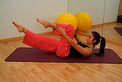 Mujer practicando una rutina de ejercicios de Pilates en colchoneta