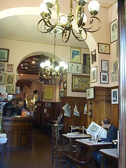 Interior del café tapizado con obras de arte, dibujos y recortes