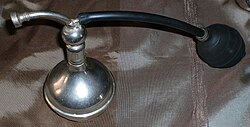Antigua talquera de plata ornamentada utilizada históricamente en salones de peluquería.