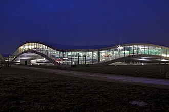 Fachada iluminada del Centre d'Apprentissage Rolex al anochecer.