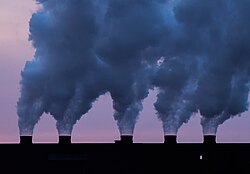 Emisiones atmosféricas y contaminantes emanando de una estructura industrial.