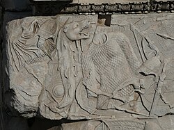 Detalle de la base de la columna decorada con trofeos de guerra y armaduras