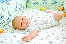 Un bebé sonriente acostado en una cuna