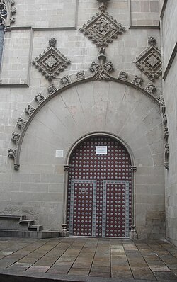 Puerta principal de la fachada gótica con escudos medievales