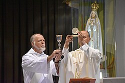Sacerdote católico elevando la hostia y el cáliz consagrados